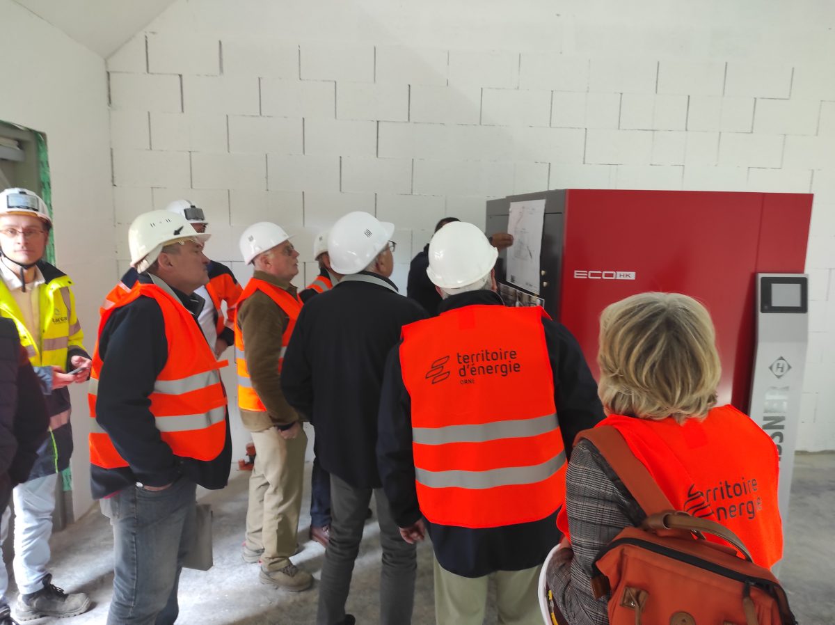 Intérieur de la chaufferie avec des personnes autour de la chaudière bois